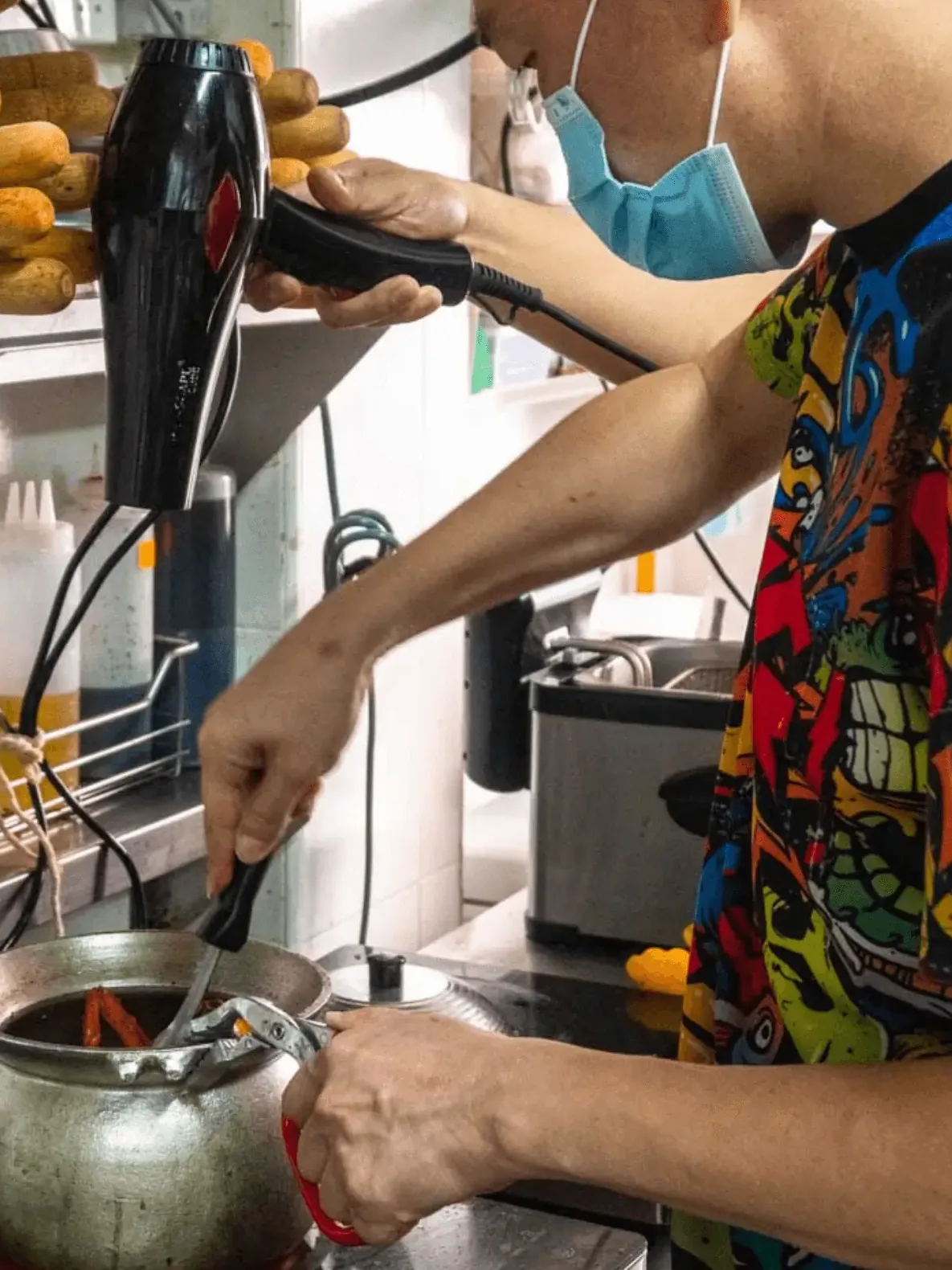 Chef pouring broth into a steelpot of prawn vermicelli